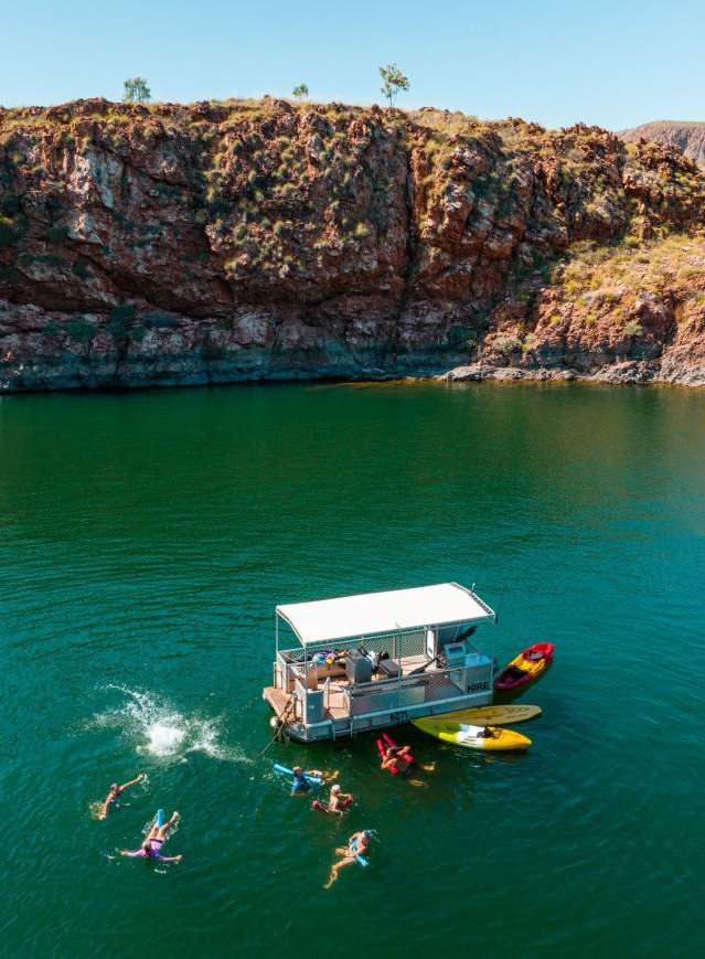A group enjoys the waters of Lake Argyle - swimming, and with kayaks and a pontoon boat.
