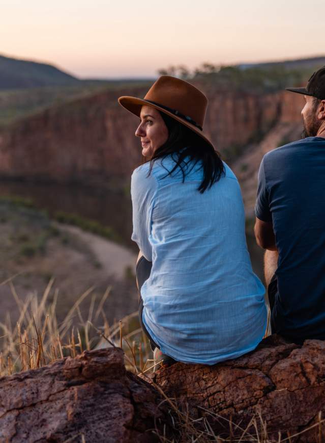 A couple sits at the Pigeon Hole lookout at El Questro, overlooking a bend in the Pentecost River
