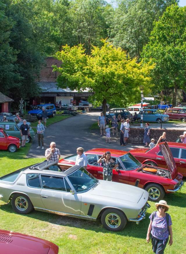 A collection of red and white classic cars parked on the lawn at Amberley Museum