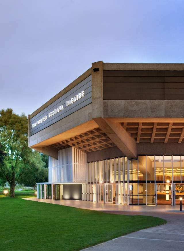 Exterior of the square roof of Chichester Festival Theatre building lit up at night