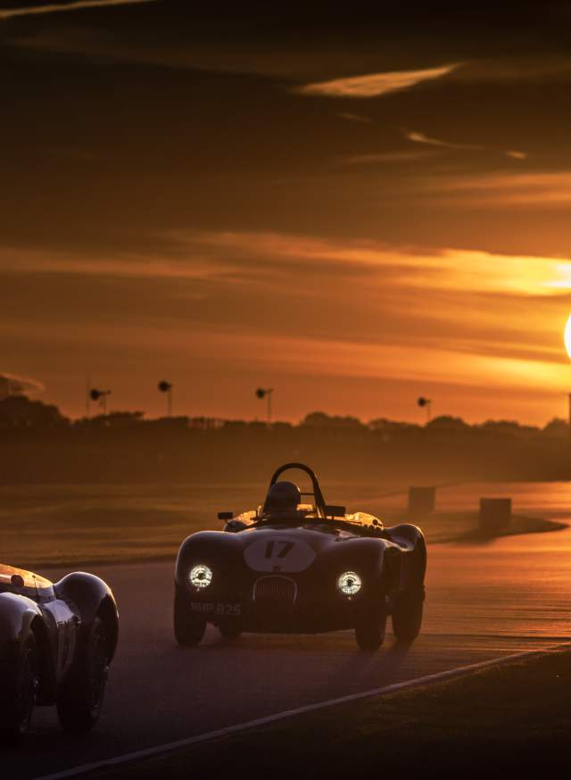 Cars race on the circuit at sunset at Goodwood Revival in Sussex
