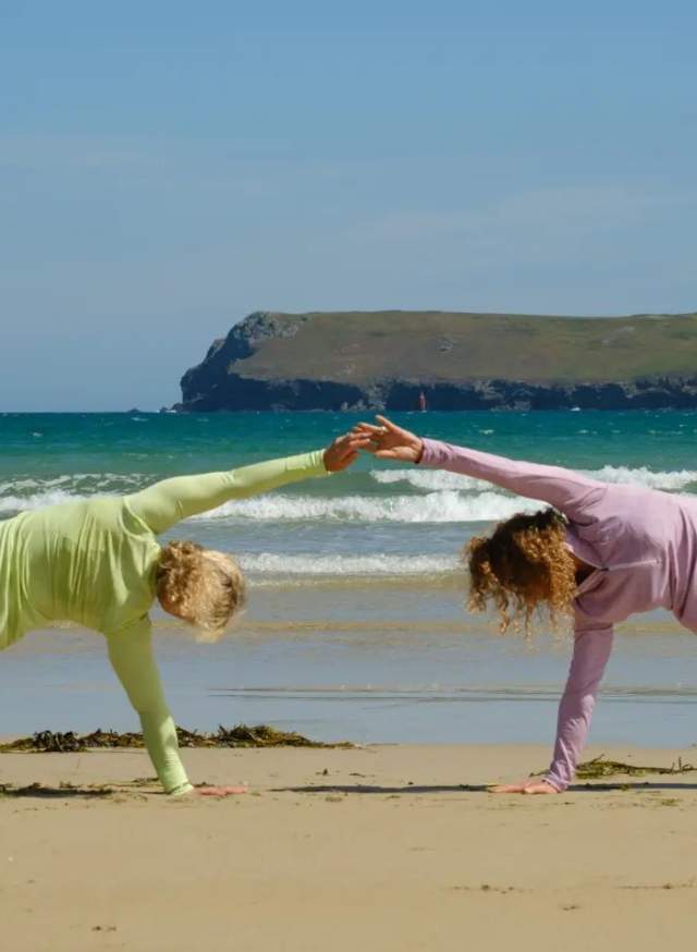 Two people doing yoga on the sandy beach at the Witterings