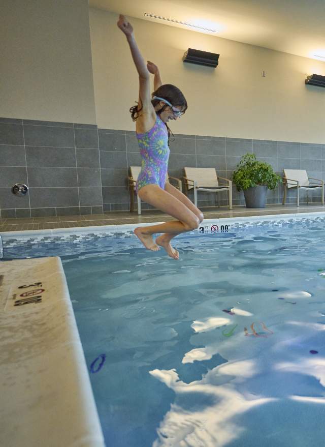 Girl jumping into the pool with dad