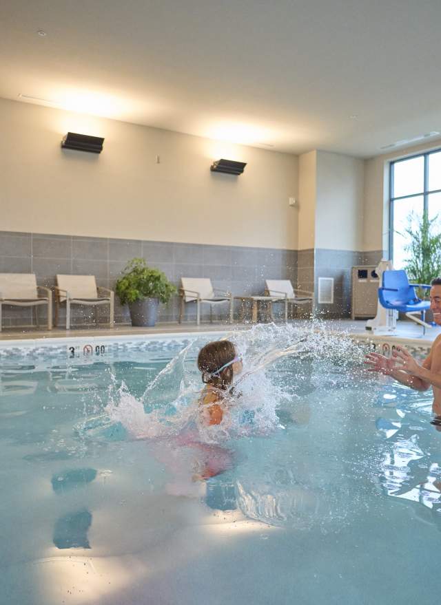 Man and daughter splashing in the pool