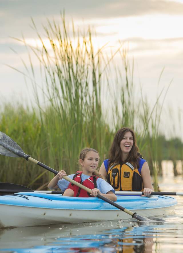 One adult and one child paddling on a kayak.