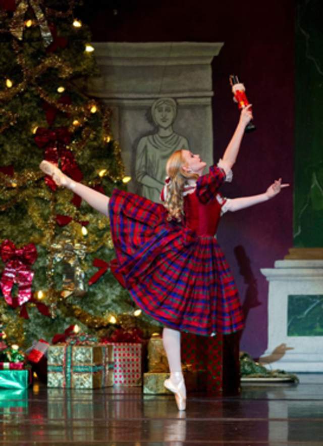 ballerina in a plaid dress posing in front of a Christmas tree