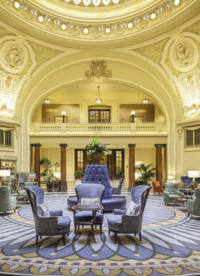 Ornate historical lobby with seating in the middle and a round skylight