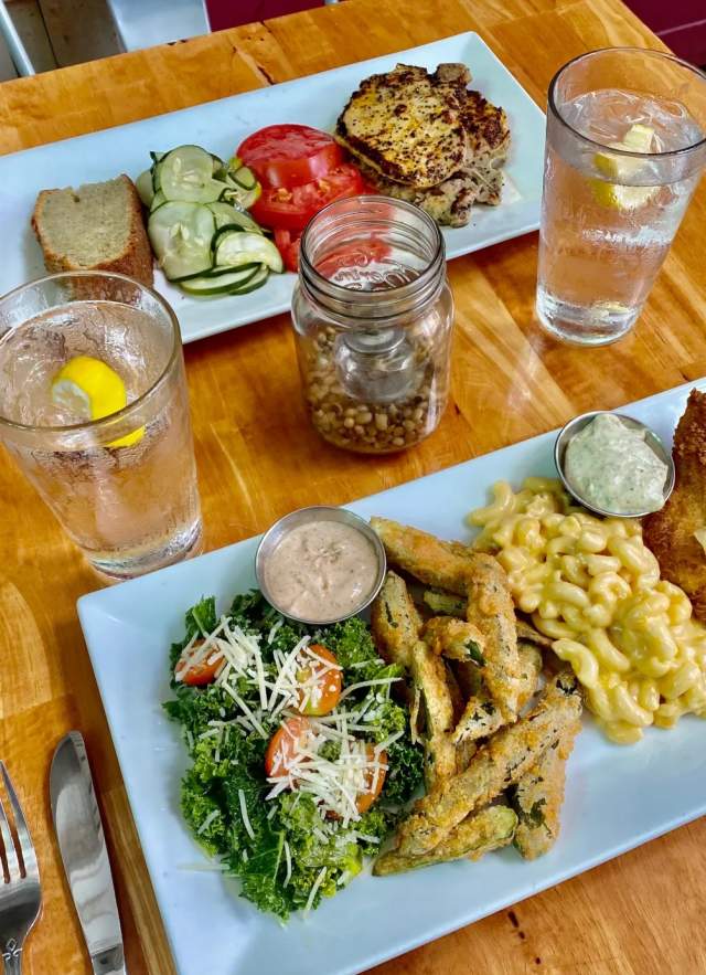 two plates of food on a table - fish, mac and cheese, fries, greens