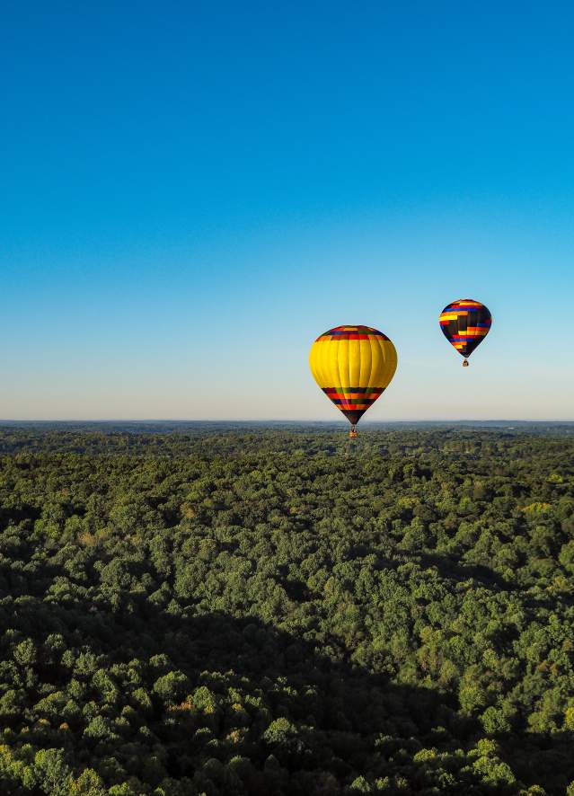 Two hot air balloons floating over Bloomington's rolling hills