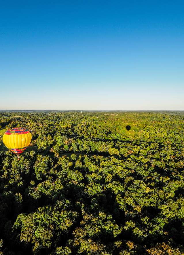 Two hot air balloons floating over the rolling hills of Monroe County