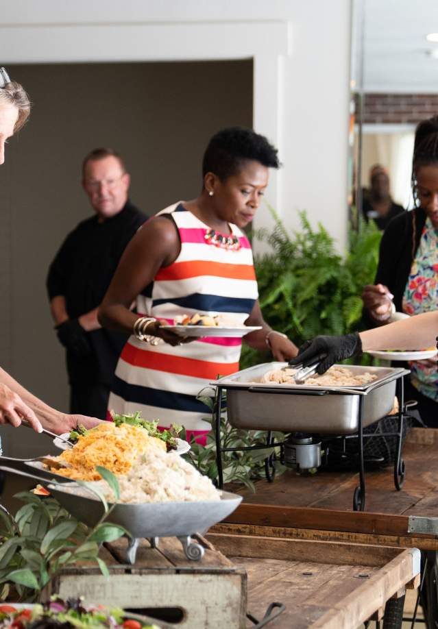 a woman serves food at a buffet line