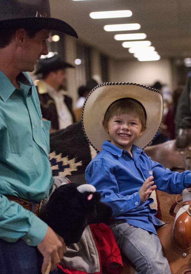 young boy smiling wearing a cowboy hat in a crowd of people