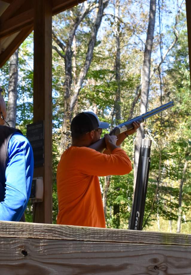 two men at a target clay shooting station in the woods