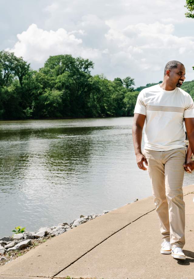 a man and woman walk along a riverside path