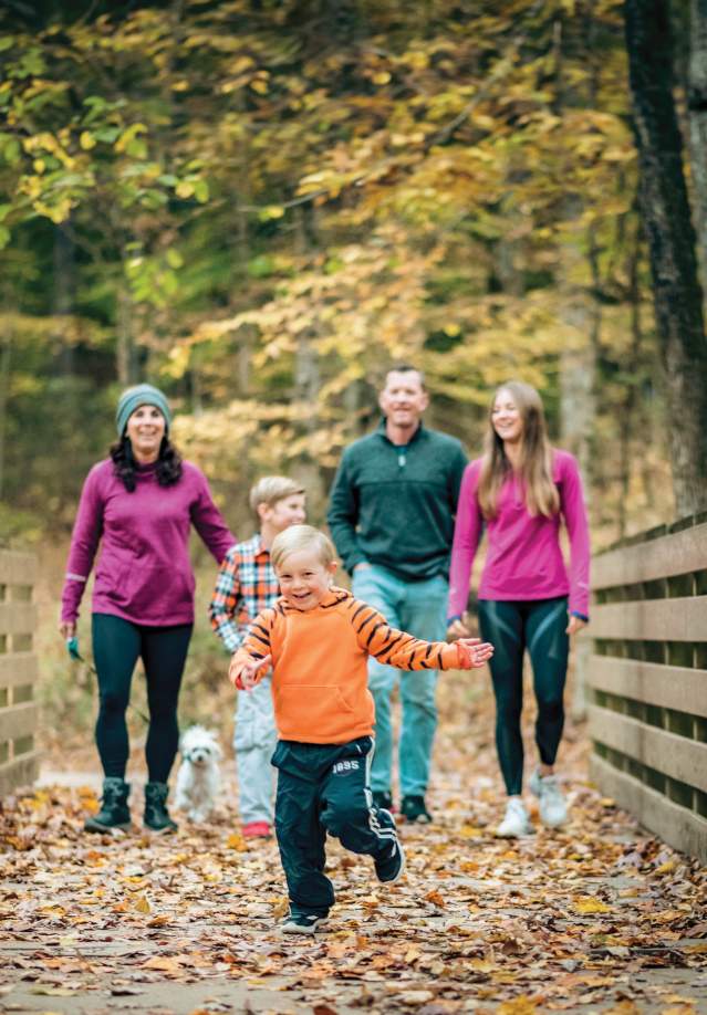 Family walks on trail in Rotary Park during the fall time.
