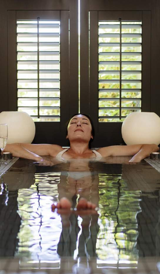 A lady soaking in a small hot pool with candles surrounding