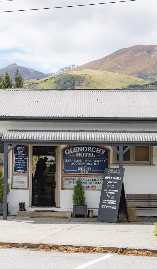 Exterior shot of Glenorchy hotel and pub which old school signage and mountains in the background