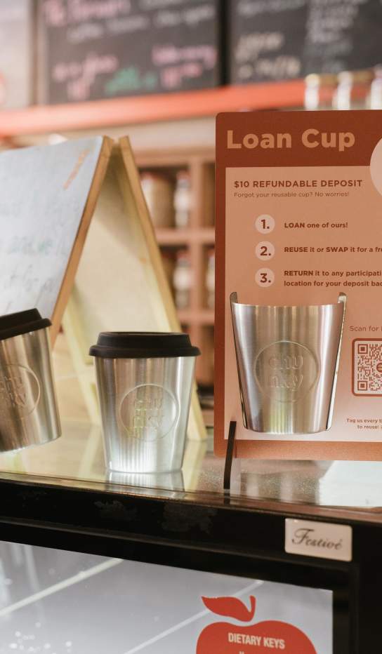 Reusable loan coffee cups displayed on a cafe cabinet
