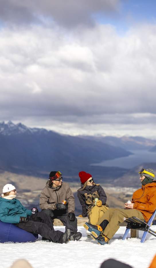 Group of skiers and snowboarders having a drink at the top of a mountain