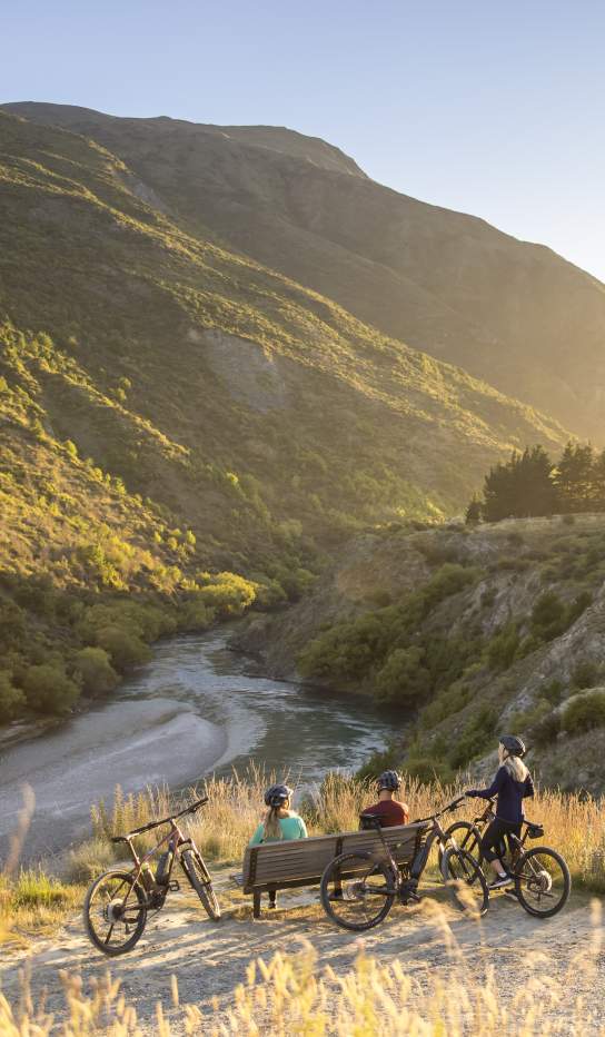A group of cyclists taking a break next to Gibbston River