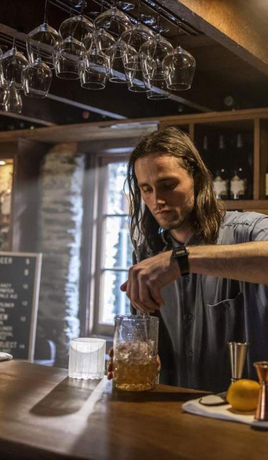 Bartender mixing a cocktail at The Blue Door bar in Arrowtown.
