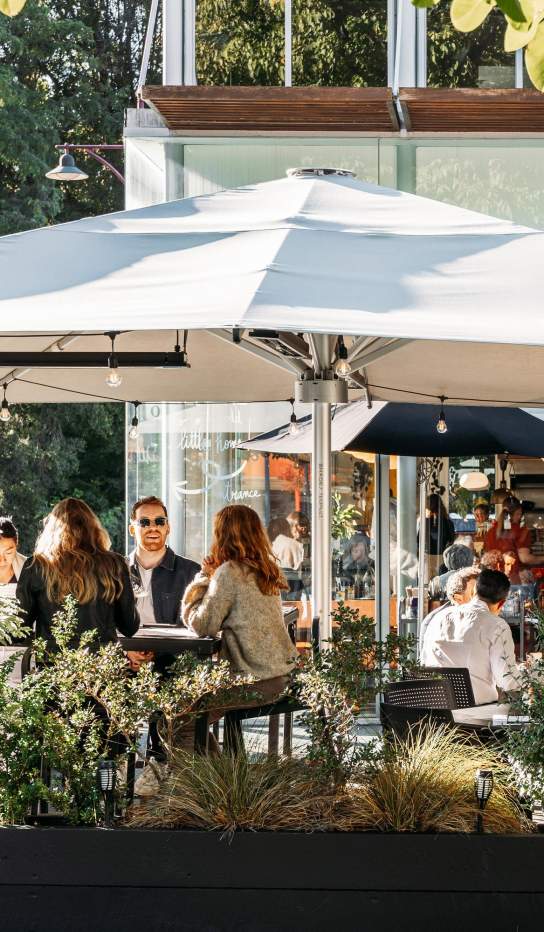 View of a people sitting in a cafe courtyard surrounded with greenery