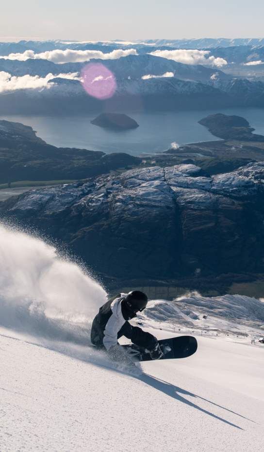Snowboarder at Treble Cone with lakes and mountains in the background