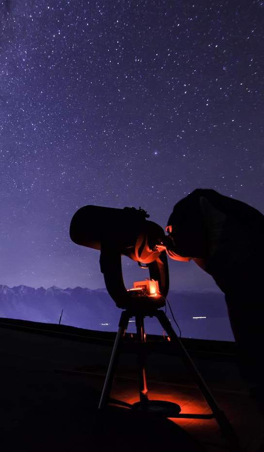 Person with telescope stargazing underneath the milky way near The Remarkables mountain range