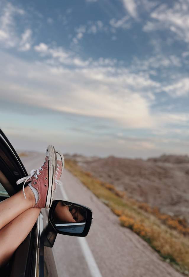 Car driving down the road with the view of Badlands National Park ahead