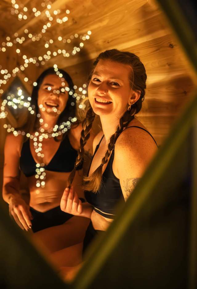 Looking through a sauna window at two women smiling.