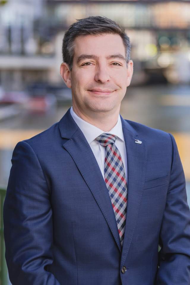 Matt Dorner in a navy suit, with a blue and red crosshatched tie, smiling in a headshot.