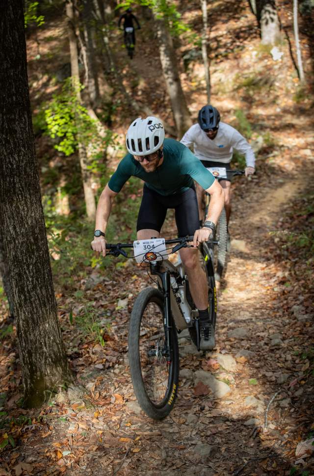 Two racers ride their mountain bikes uphill at the Oak Ass 100 endurance race.