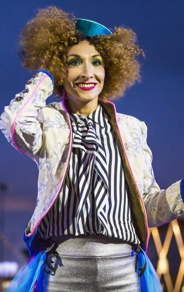 Performer in bright clothing from Transe Express theatre company in front of the Cristal Palace Chandelier