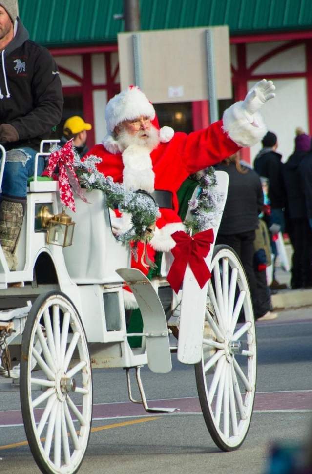 Santa waves to parade crowd from vintage horse drawn carriage