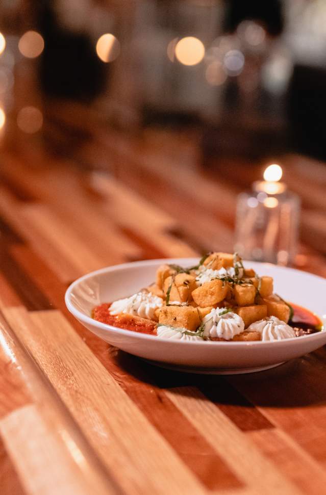 bowl of gnocci and chredded cheese sits on wooden table in restaurant