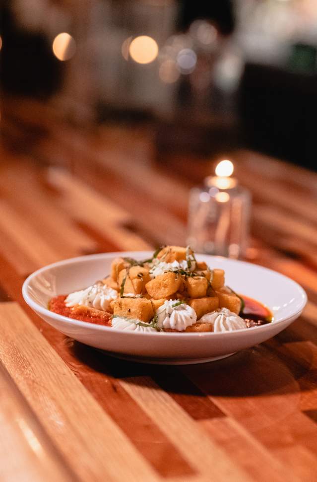 bowl of gnocci and chredded cheese sits on wooden table in restaurant