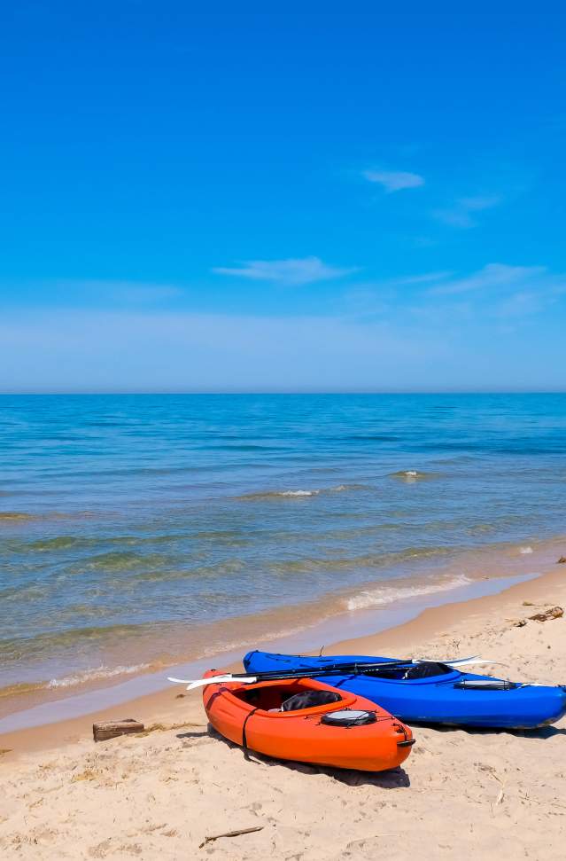 orange and blue kayaks on shore of beach, blue sky