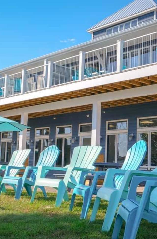 light blue lawn chairs lined up in front of dark blue inn with large balcony