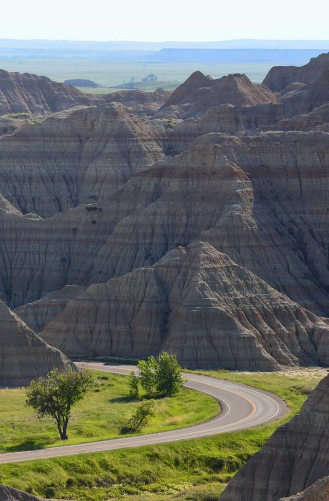 road driving into the towering landscape of badlands national park in south dakota