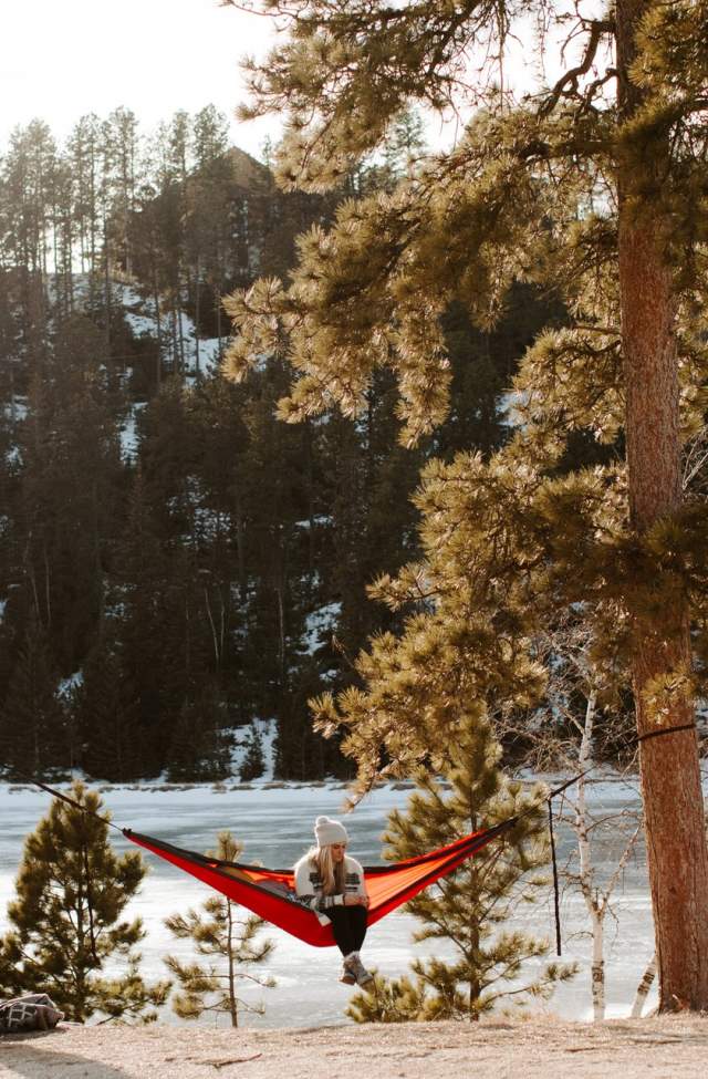 person reading in a hammock in front of a lake in the black hills of south dakota