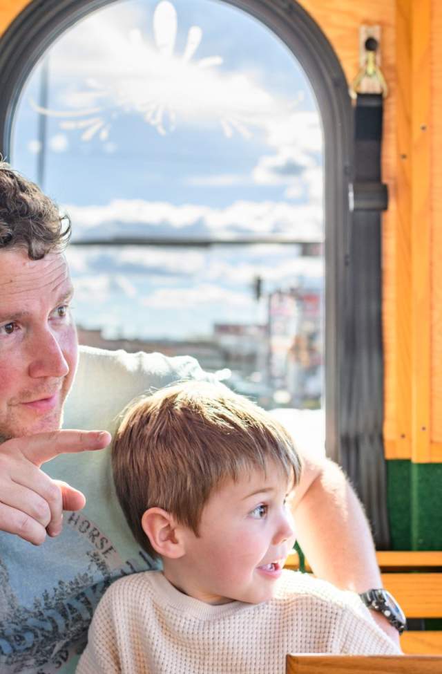 father and son looking out the windows of the city view trolley tour in rapid city,sd