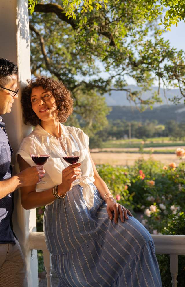 a male female couple on the porch of Beltane Ranch enjoying red wine