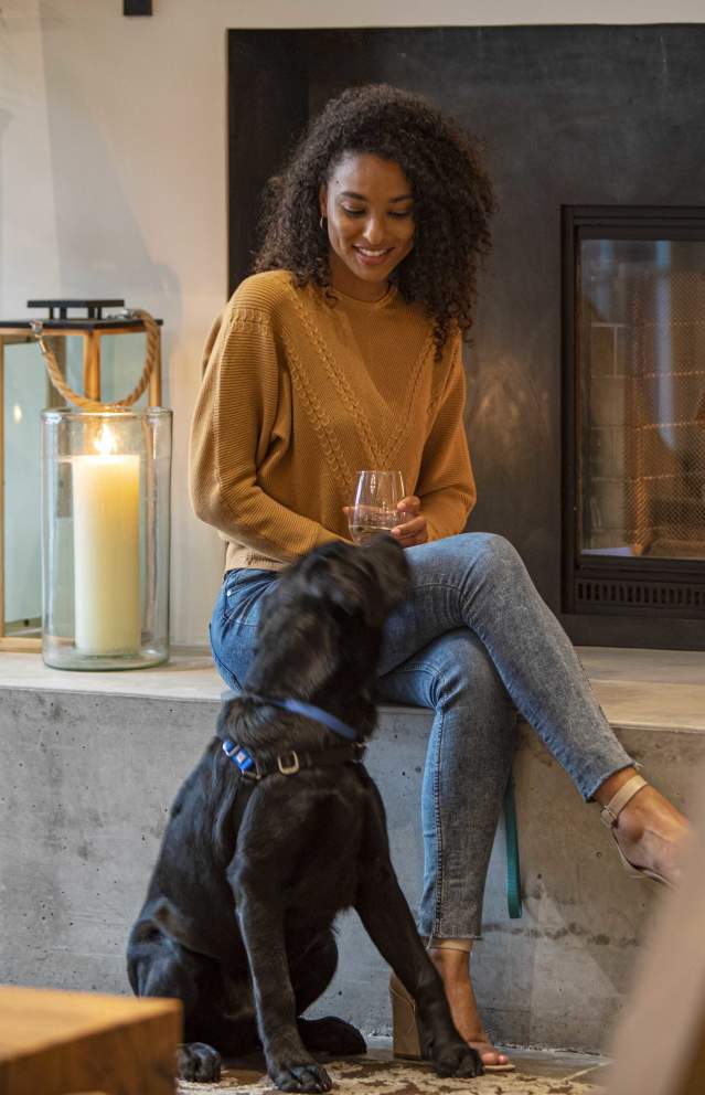 A woman enjoys a warm and cozy fireplace with her dog at the Lodge at Sonoma