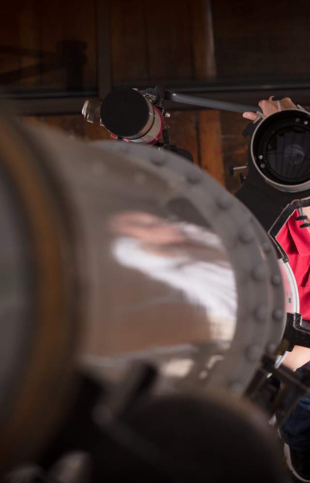A child looks through a large telescope with the help of a South Carolina State Museum employee.