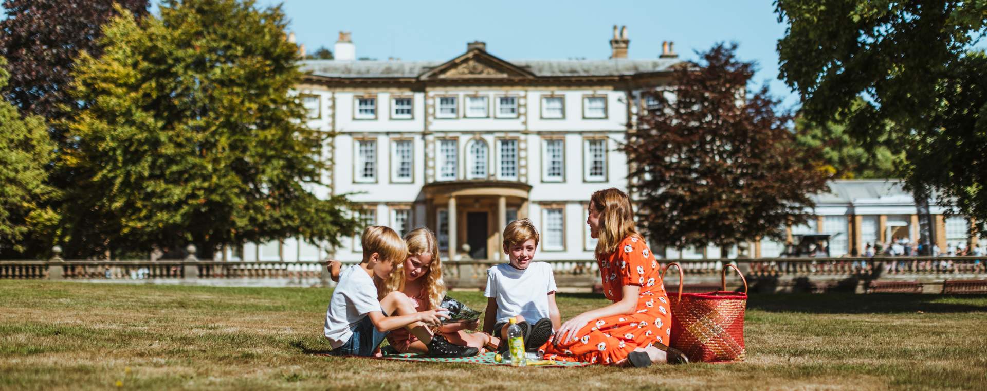 A mother and her three children enjoying a picnic on the grass in front of Sewerby Hall in Bridlington, East Yorkshire