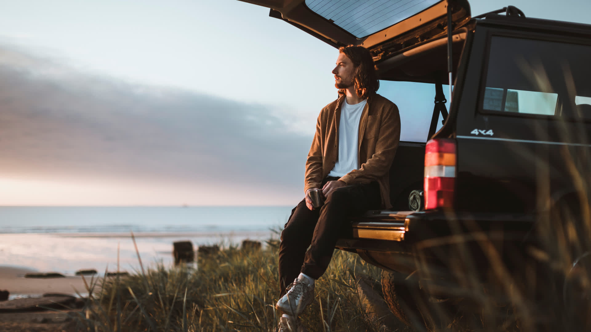 Person sat on tailgate on car next to the beach in East Yorkshire