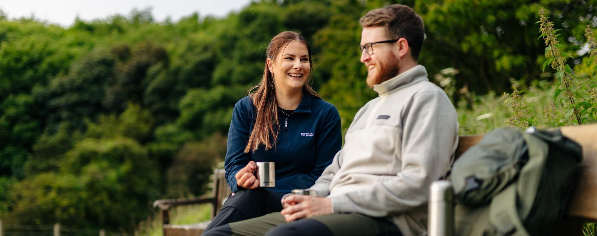 A couple enjoying a flask of hot drinks, sat on a bench taking a break from walking in the Yorkshire Wolds.