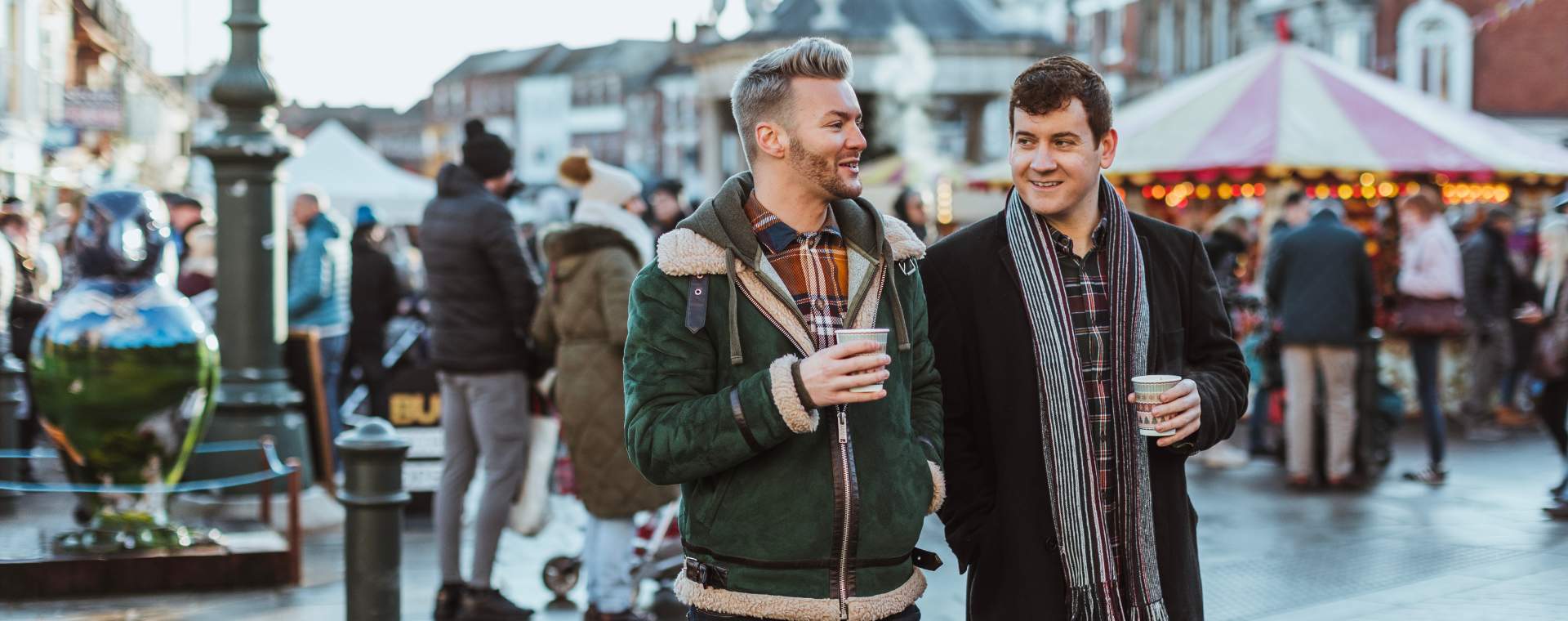 Two friends drinking hot chocolates whilst strolling around the Beverley Festival of Christmas in East Yorkshire