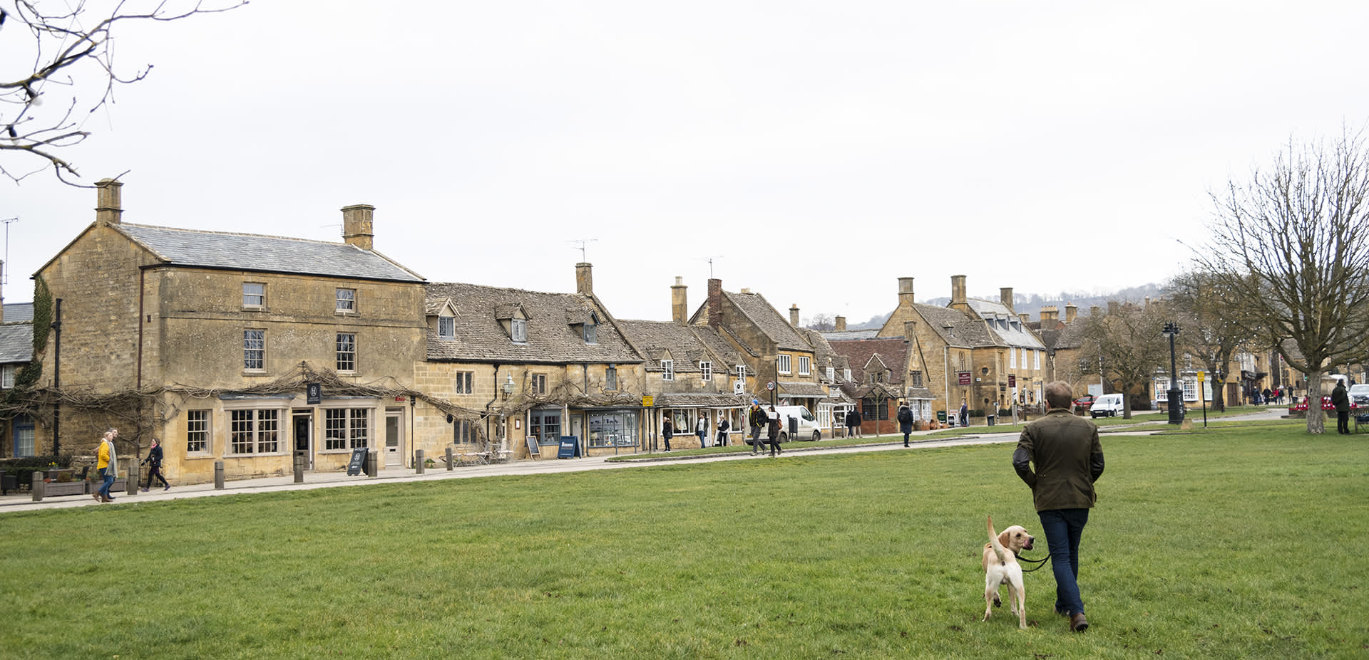 Man walking his dog across the green towards Broadway village centre