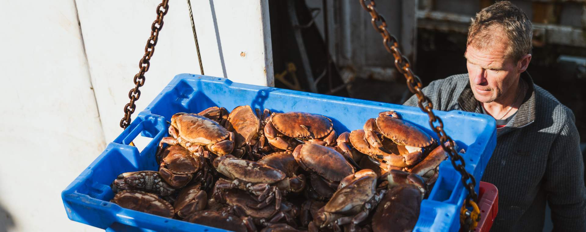 A fisherman with a large blue container filled with freshly caught Bridlington crab